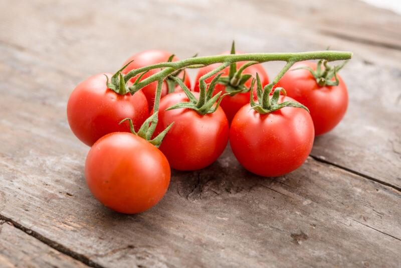 on a wooden surface is a bunch of Pomodoro di Pachino