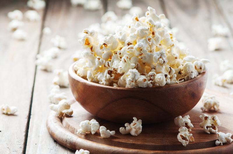 A brown bowl containing popped popcorn