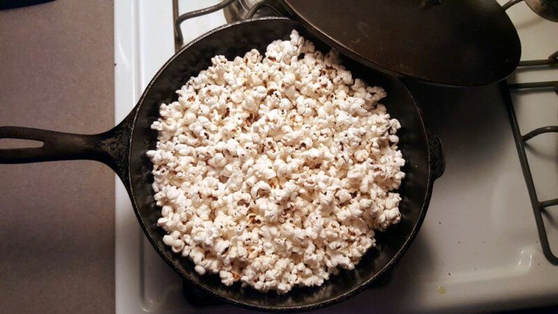 A black frypan containing freshly popped popcorn