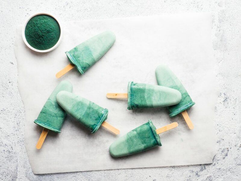 Six popsicles made using spirulina on a white table