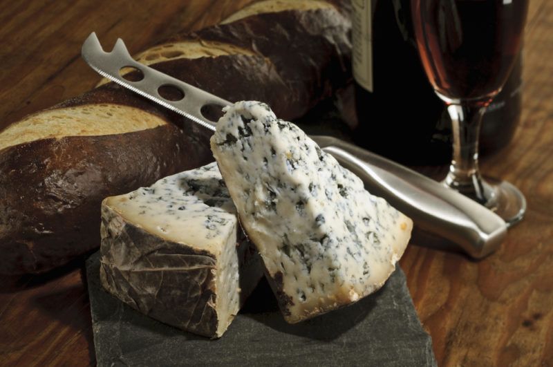 Blue cheese and bread on a board with a knife, next to a glass of port