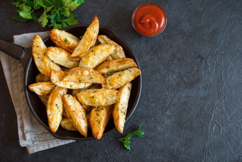 A bowl of potato wedges on a dark background