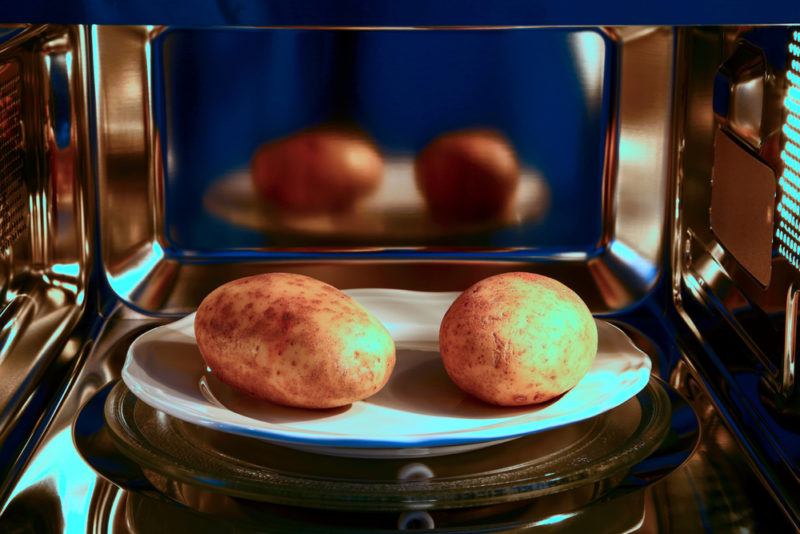 Two raw potatoes in the microwave ready to be cooked