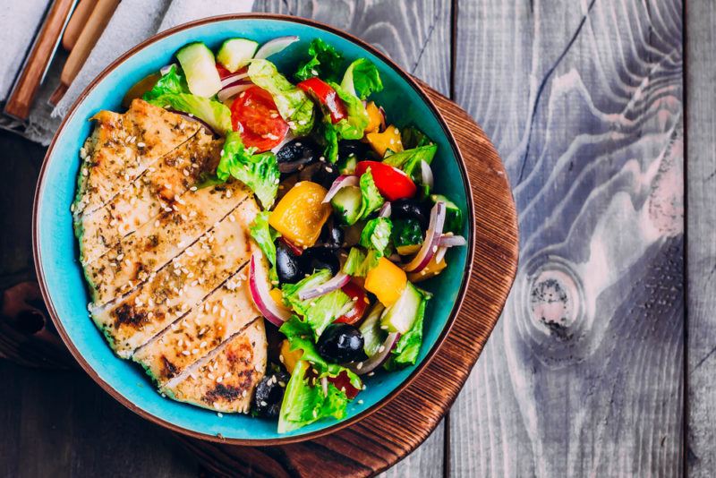 A blue plate with a salad and sliced chicken