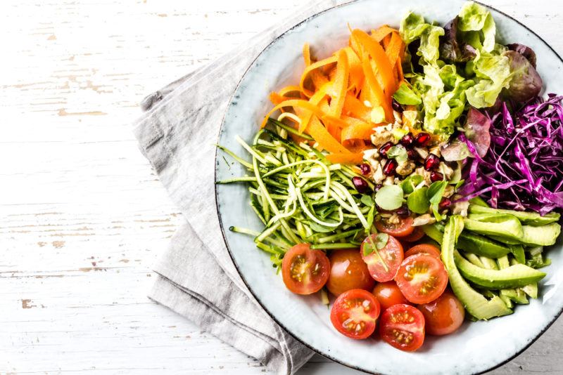 A white bowl with a large selection of fresh vegetables