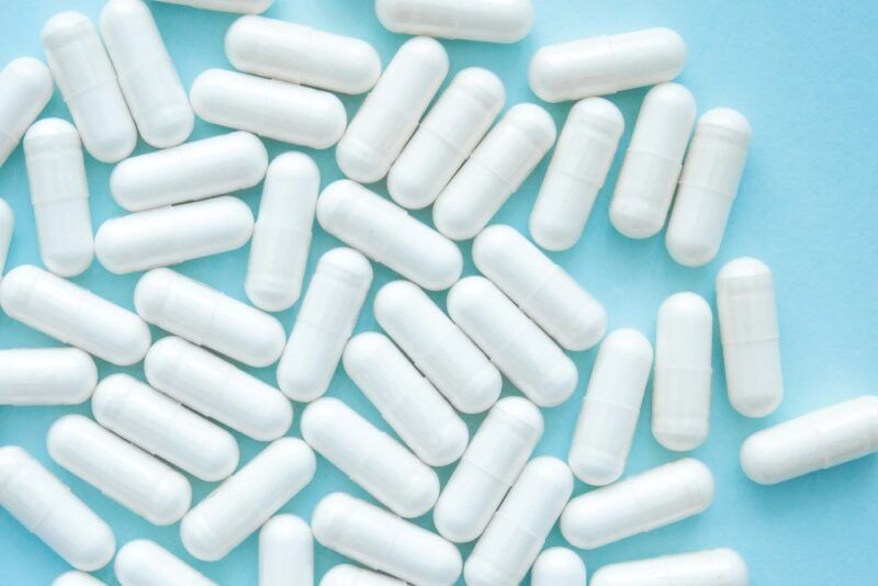 A collection of white probiotic pills on a light blue background