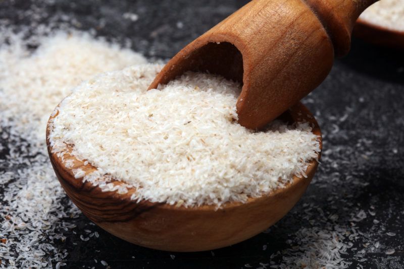 A brown bowl with psyllium husk and a spoon