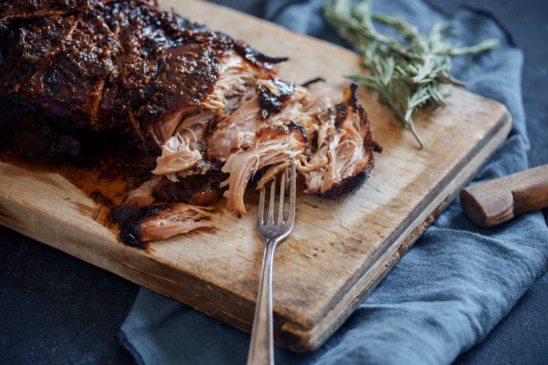 Pulled roast pork on a cutting board with a fork