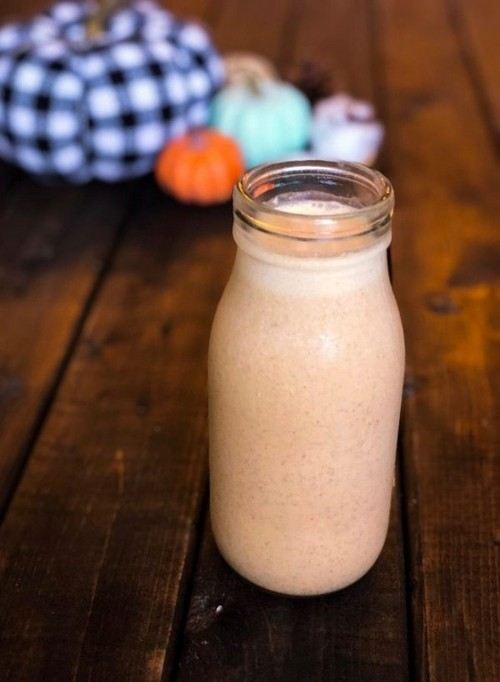 An orange pumpkin shake in a milk bottle