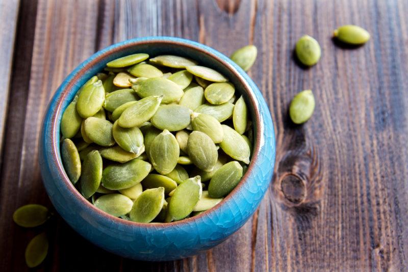 A blue bowl containing pumpkin seeds