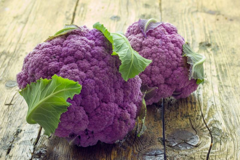 Two purple cauliflowers on a wooden table