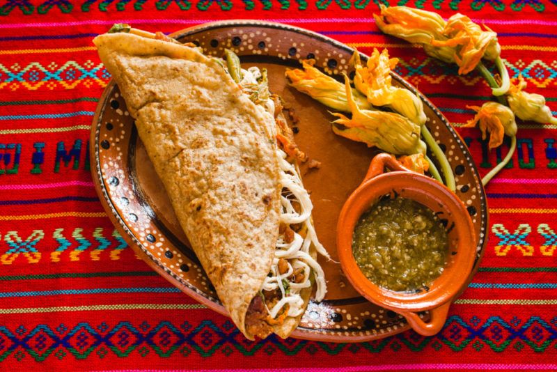 An oval plate that includes a quesadilla, salsa, and squash