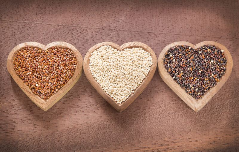 Three heart shaped bowls containing different colors of quinoa