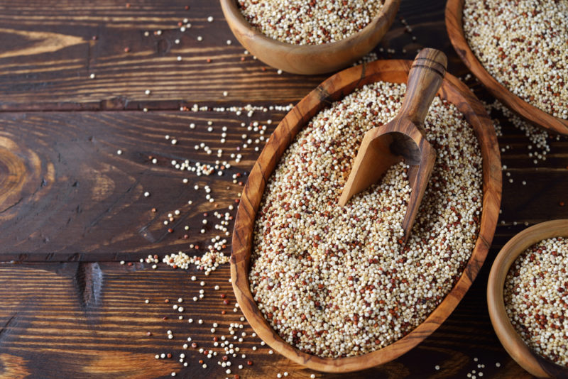 Wooden bowls of quinoa, one of which has a scoop in it