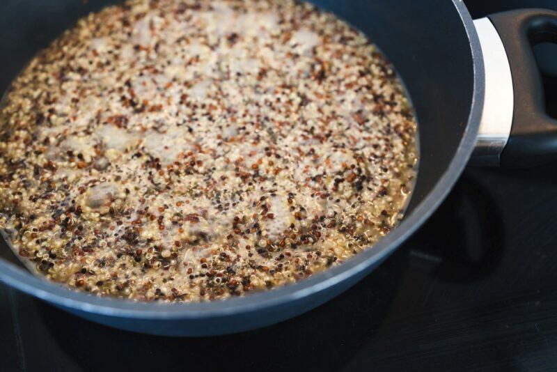 A pot boiling on the stove with quinoa and water