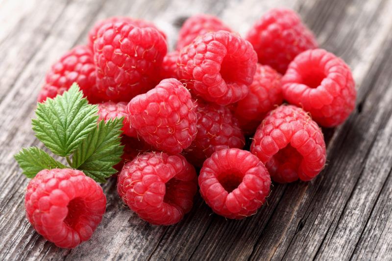 Various fresh raspberries on a wooden table or plank