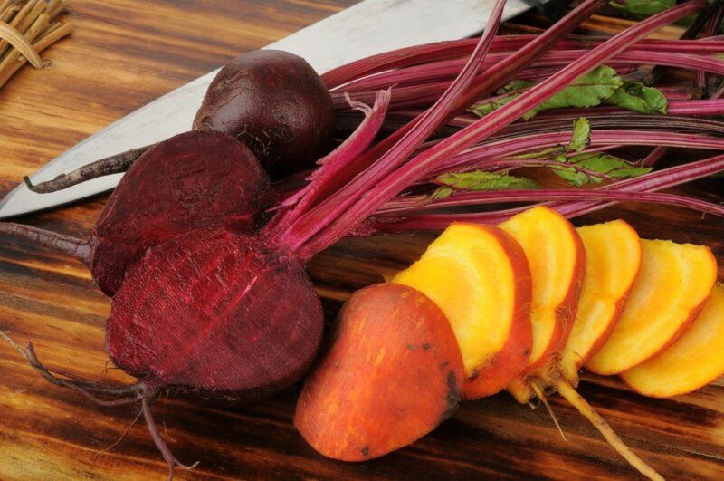 Red and golden beets that have been sliced on a board