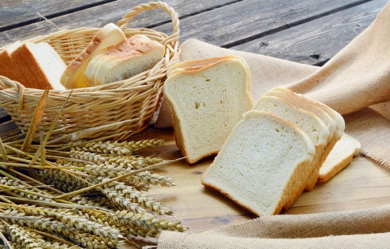 A basket of sliced white bread and pieces of bread on a board