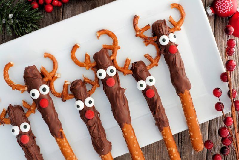 A white board with chocolate dipped pretzel sticks that have been decorated to look like reindeer