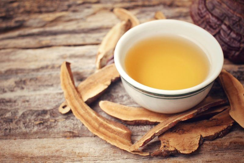 A white bowl of reishi mushroom tea with the dried mushrooms next to it