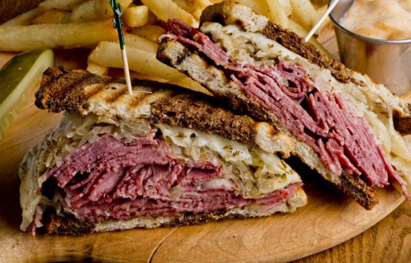 Rubens that have been made using corned beef and grilled, with fries in the background