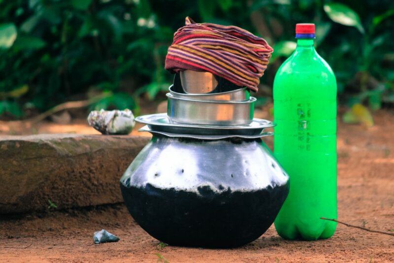 A green plastic bottle of rice beer next to a pot