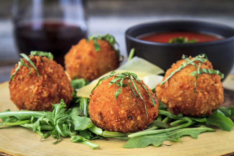 Fried risotto balls on a bed of microgreens, served with some marinara sauce. 