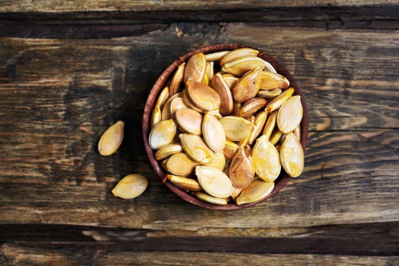 Roasted pumpkin seeds on a wooden table. 