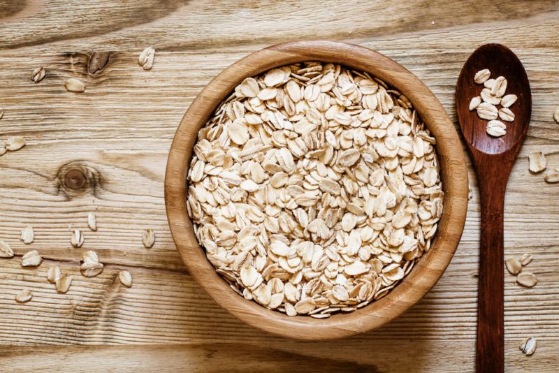 A bowl with rolled oats, next to a spoon