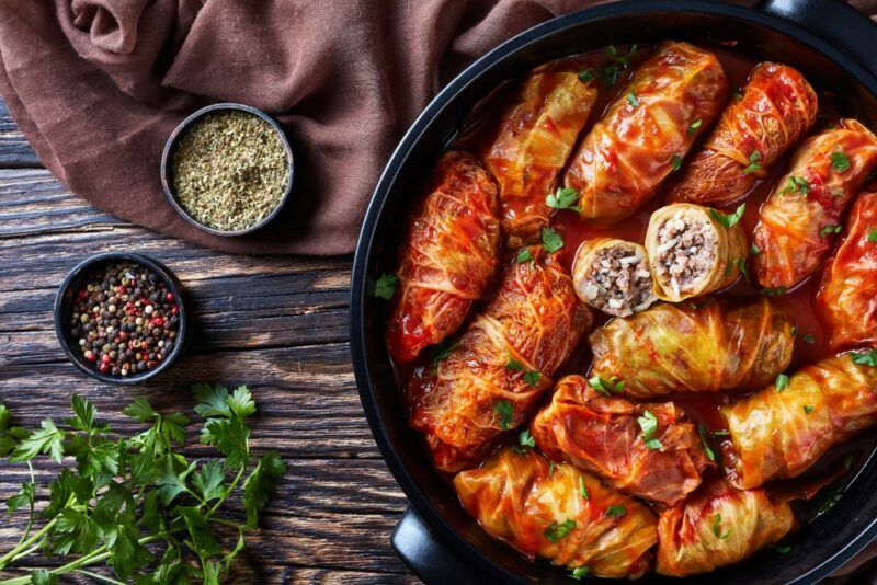 A black dish filled with rolls that have been wrapped in eggplant leaves