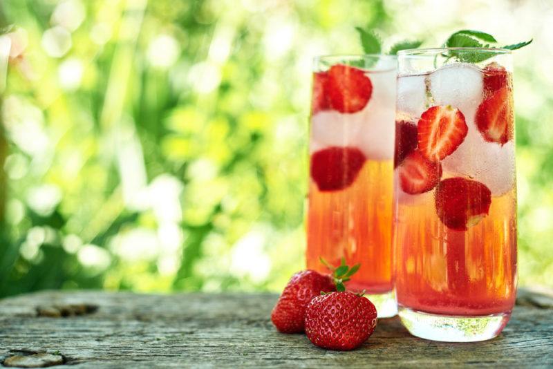 Two glasses of rose spritz with ice, strawberries and mint leaves