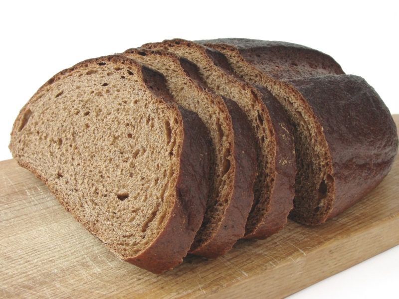 a loaf of rye bread on top of a wooden chopping board