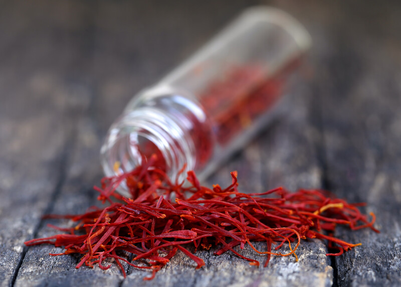 saffron threads pouring out of a small thin toppled over spice bottle