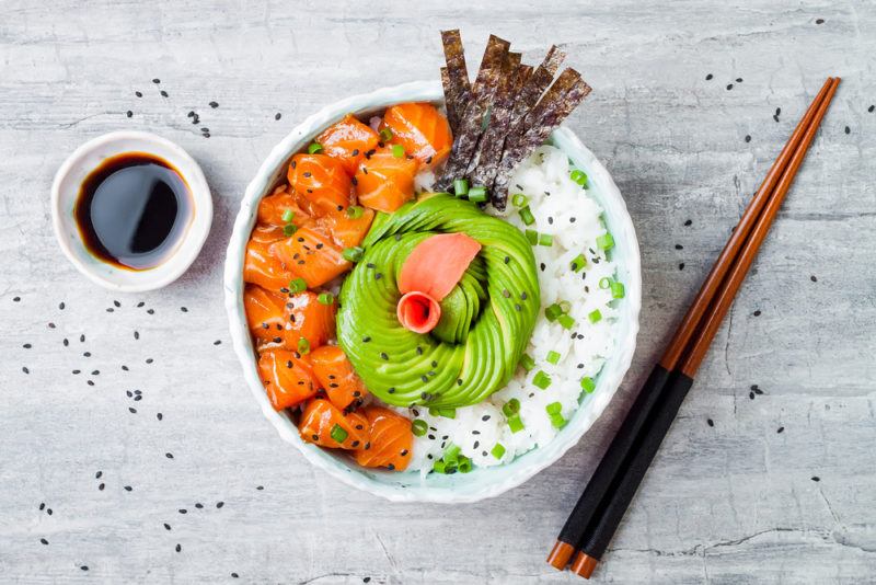 A salmon poke bowl that includes avocado, salmon, seaweed and rice