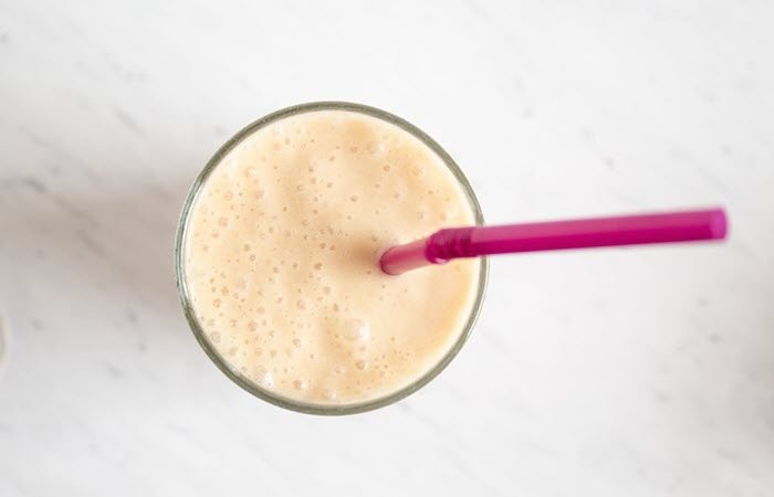 A top down image of a caramel smoothie with a pink straw