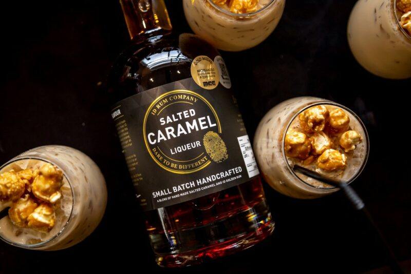 A bottle of salted caramel liqueur surrounded by four salted caramel liqueur cocktails