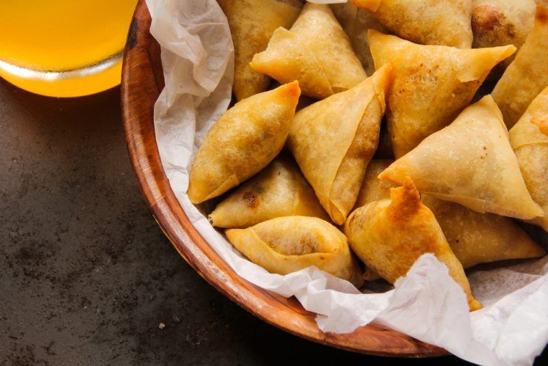 A brown bowl of samosas that have been cooked for a party