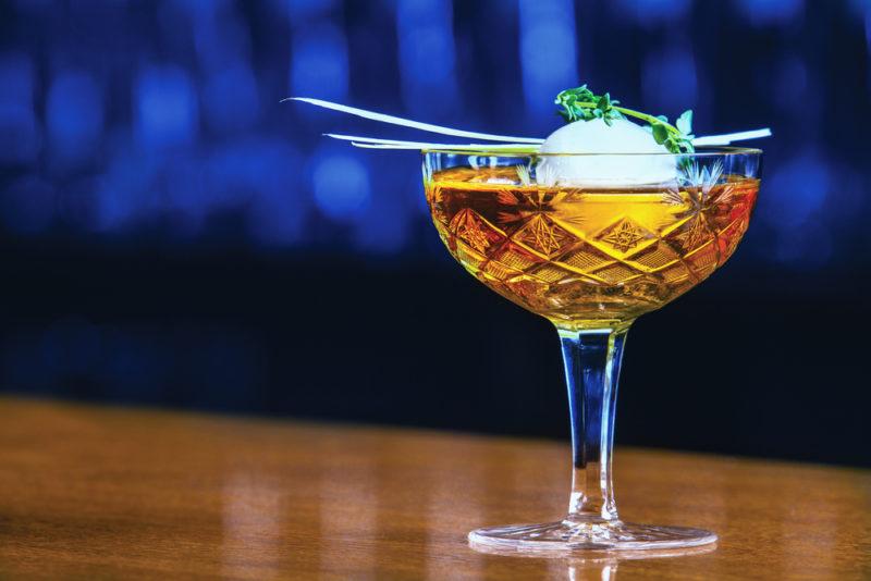 A Saratoga cocktail on a bar against a blue background