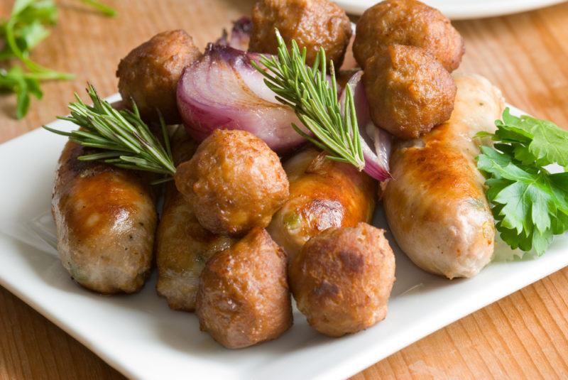 A white plate with sausage balls and some herbs