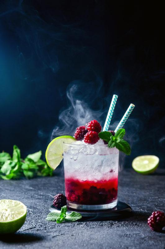 A rocks glass with a berry cocktail that has been topped with soda water