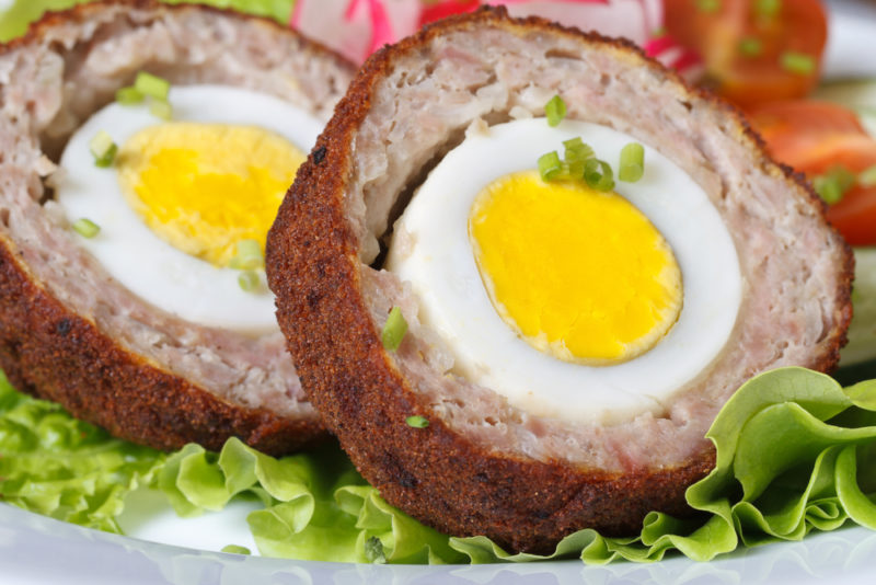 Two halves of a Scotch egg on a plate