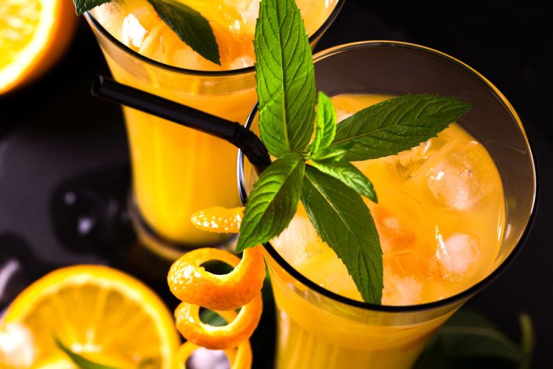 A close up image of two vodka screwdrivers with a spiral and a slice of orange