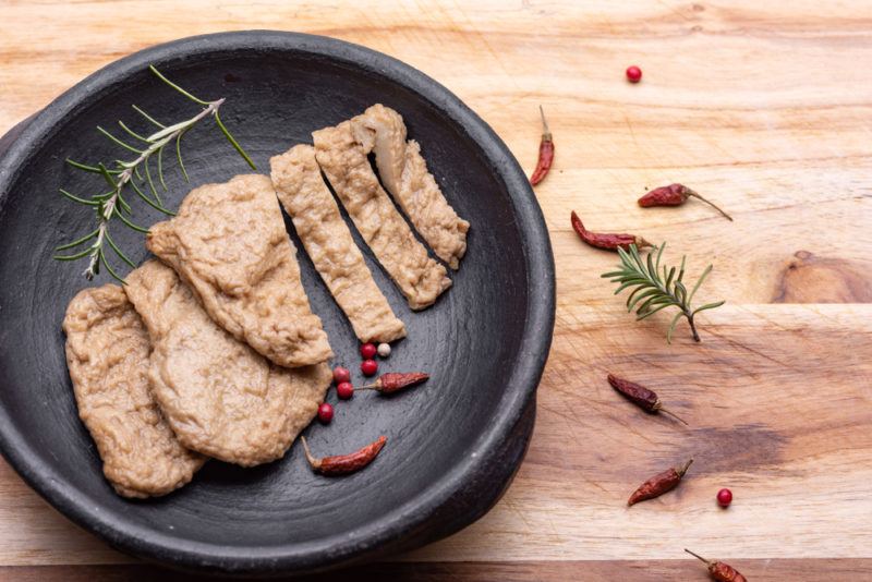 A black plate containing seitan meat