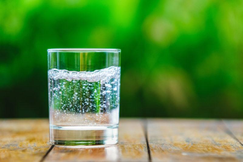 A glass of sparkling seltzer against a green background