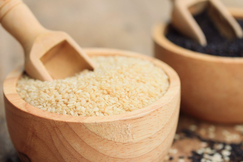 sesame seeds in a wooden bowl with wooden scoop in it