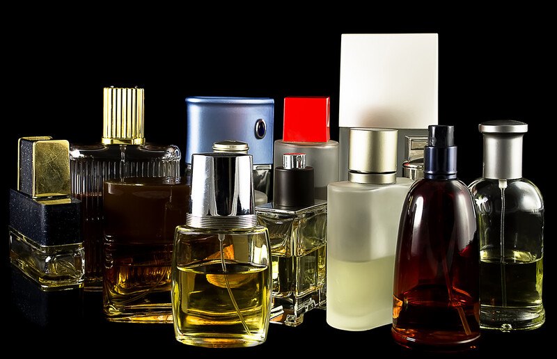 Several bottles of men's cologne set against a black background