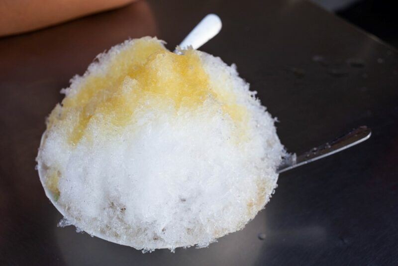 A large serving of shaved ice or a snow cone, with yellow syrup to make a Bart Simpson snow cone