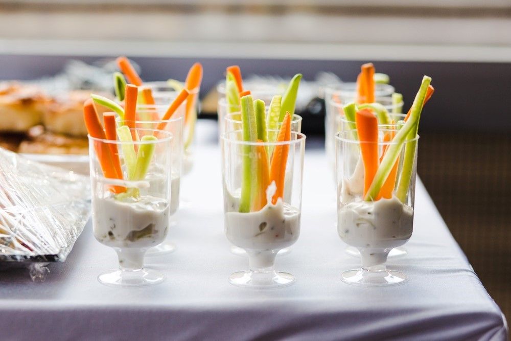 A selection of shot glasses with dip at the bottom and cut veggies sticking out of them