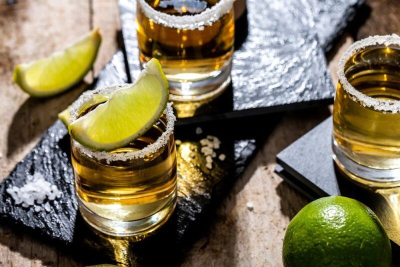 Shots of tequila on black slates, with wedges of lime