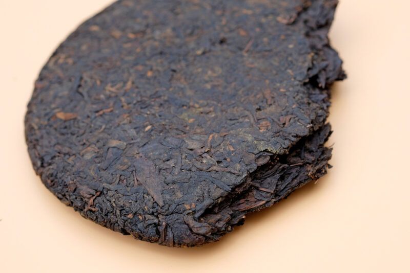 on a brown surface is a partial round pressed Shou Pu-Erh tea